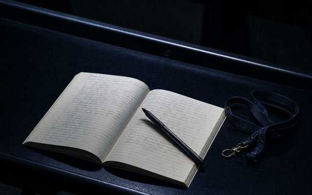 An open notebook and pen on a lecture bench